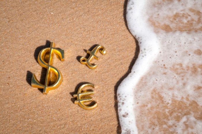 Currency symbols on the sand of tax havens