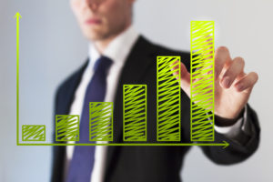 Businessman looks at green graph showing growth