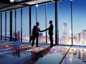 Businessmen shaking hands in from of cityscape