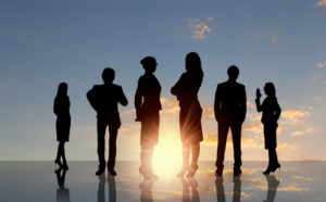 Sun rising behind a group of business people