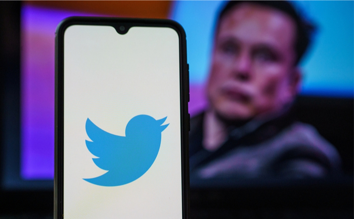 Twitter logo with Elon Musk in the background